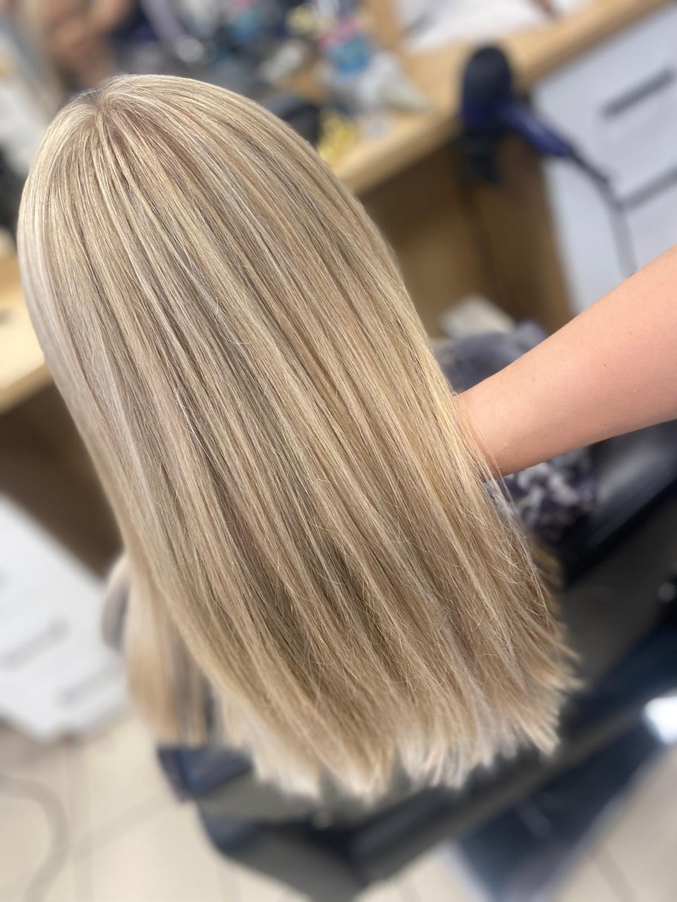 Gładkie proste blond włosy z jaśniejszymi pasmami i równą linią końcówek.